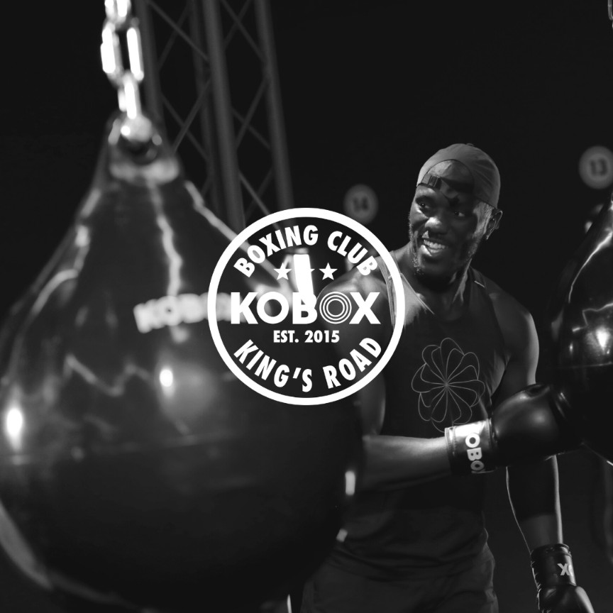 KOBOX client training with a heavy bag during a high-energy boxing class at King’s Road studio, combining power, cardio, and nightclub-style atmosphere.