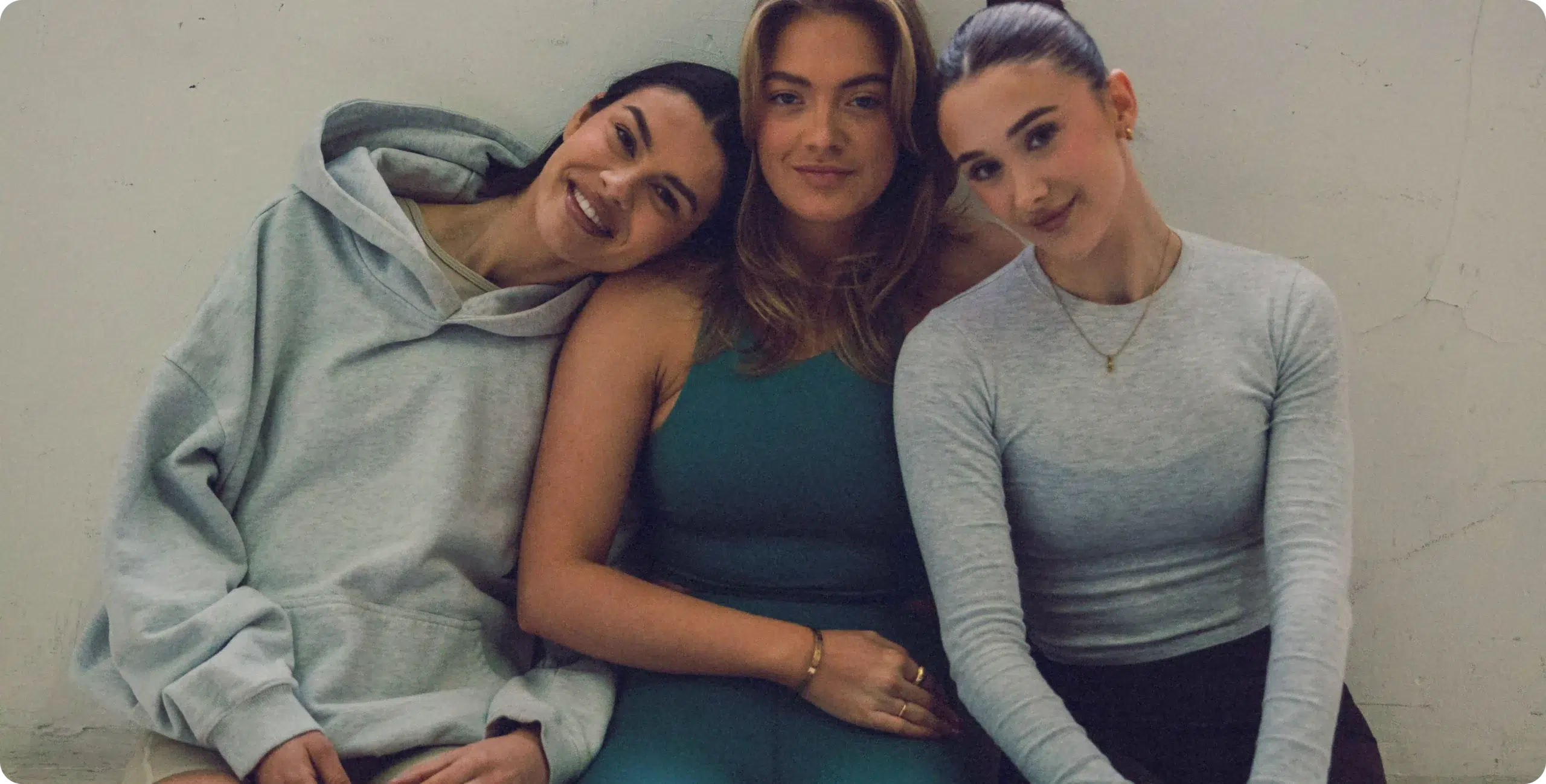 Three women seated and smiling after a Barrecore class, wearing studio activewear in a relaxed post-workout moment.